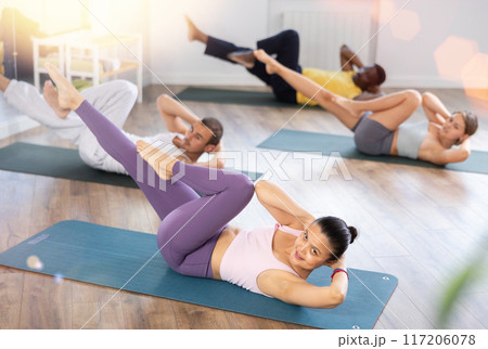 Asian woman doing bicycle crunches during group pilates training 117206078