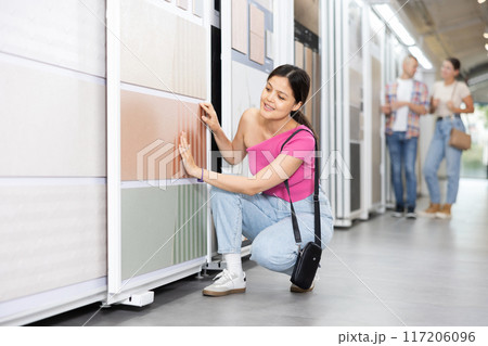 Positive woman wants to buy stone technical tiles for flooring or wall cladding in the materials department of hardware store 117206096