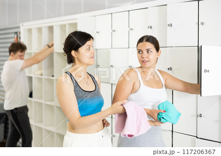 Two athletic girls have a conversation in gym locker room Two athletic girls have a conversation in gym locker room 117206367