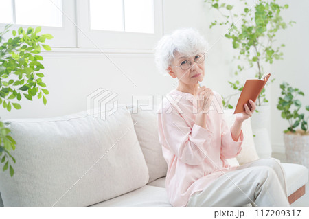 手帳にメモするシニア女性 手帳にメモするシニア女性 117209317