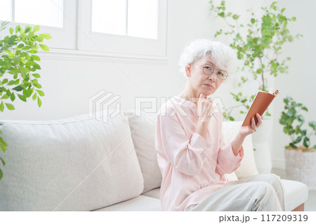 手帳にメモするシニア女性 手帳にメモするシニア女性 117209319