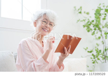 手帳にメモするシニア女性 117209320