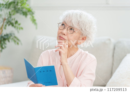 年金手帳を見るシニア女性 117209513