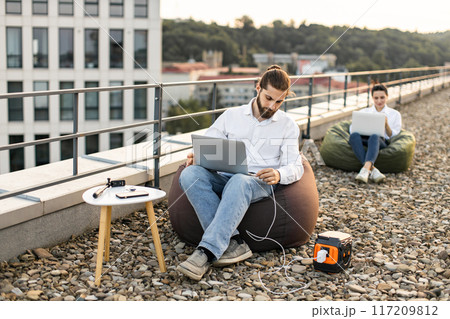 Business man working on rooftop with portable power station 117209812