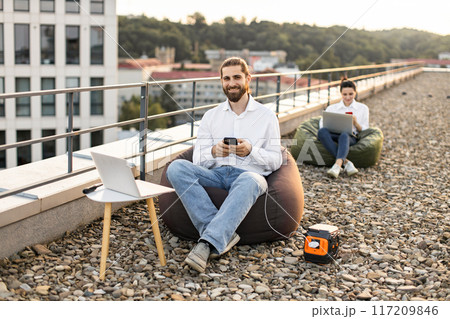 Businessman charging phone on rooftop with portable power station 117209846