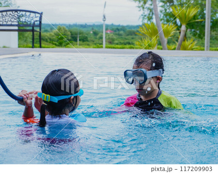 Two little girls have fun playing in the outdoor swimming pool. Two little girls have fun playing in the outdoor swimming pool. 117209903