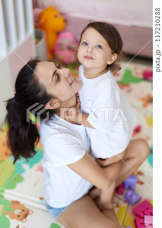 happy mother with cute baby girl in white t-shirt having fun together happy mother with cute baby girl in white t-shirt having fun together 117210288