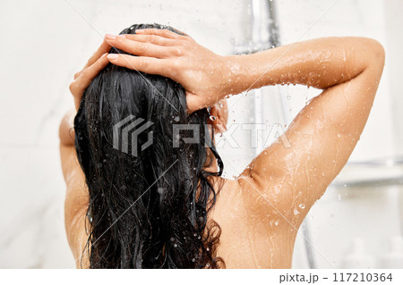Young woman taking refreshing shower in marble bathroom. Girl washing her hair, back view 117210364