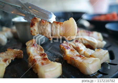 Grilled pork belly being grilled on black grill, close-up 117210782