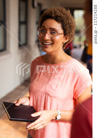 Smiling teenager holding notebook, standing in high school hallway, wearing glasses Smiling teenager holding notebook, standing in high school hallway, wearing glasses 117214288