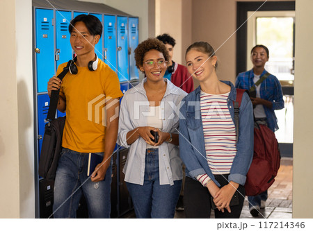 Walking in high school hallway, teenagers smiling and carrying backpacks Walking in high school hallway, teenagers smiling and carrying backpacks 117214346