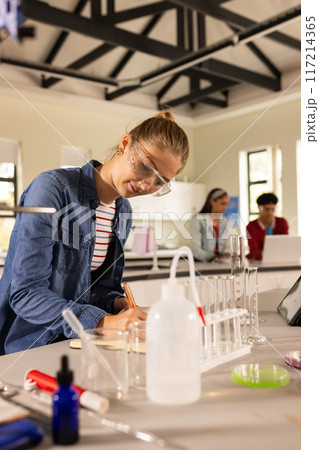 Conducting science experiment in high school laboratory, teenage girl wearing safety goggles Conducting science experiment in high school laboratory, teenage girl wearing safety goggles 117214365