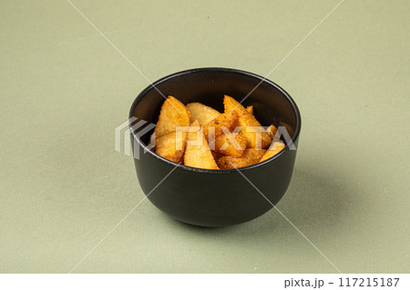Portion of baked potato wedges in black bowl 117215187