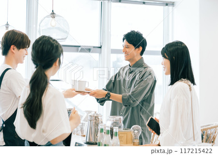 カフェスタッフとお客さんのコーヒーの受け渡し カフェスタッフとお客さんのコーヒーの受け渡し 117215422