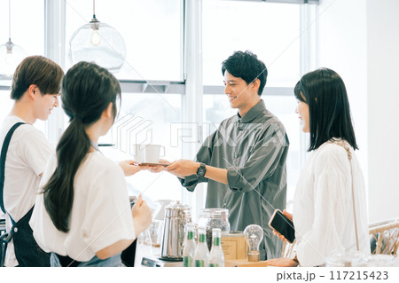 カフェスタッフとお客さんのコーヒーの受け渡し カフェスタッフとお客さんのコーヒーの受け渡し 117215423