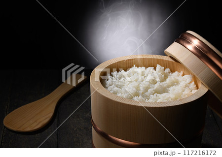お櫃に入れた炊きたて熱々の湯気が上がるご飯 (黒背景) お櫃に入れた炊きたて熱々の湯気が上がるご飯 (黒背景) 117216172