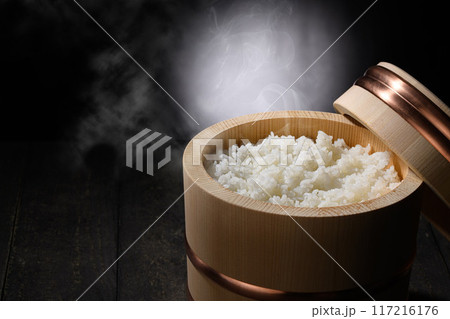 お櫃に入れた炊きたて熱々の湯気が上がるご飯 (黒背景) お櫃に入れた炊きたて熱々の湯気が上がるご飯 (黒背景) 117216176