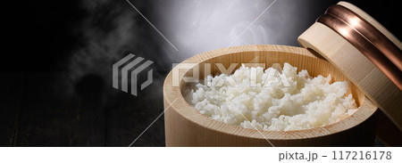 お櫃に入れた炊きたて熱々の湯気が上がるご飯 （黒背景） 117216178