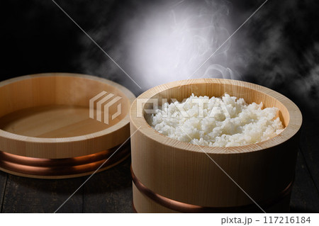 お櫃に入れた炊きたて熱々の湯気が上がるご飯 (黒背景) お櫃に入れた炊きたて熱々の湯気が上がるご飯 (黒背景) 117216184
