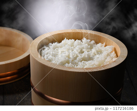 お櫃に入れた炊きたて熱々の湯気が上がるご飯 (黒背景) お櫃に入れた炊きたて熱々の湯気が上がるご飯 (黒背景) 117216186