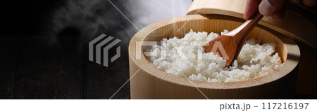 お櫃に入れた炊きたて熱々の湯気が上がるご飯 (黒背景) お櫃に入れた炊きたて熱々の湯気が上がるご飯 (黒背景) 117216197