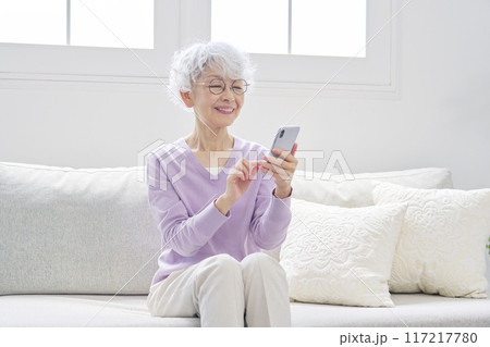 スマートフォンを使うシニア女性　リビングルーム 117217780