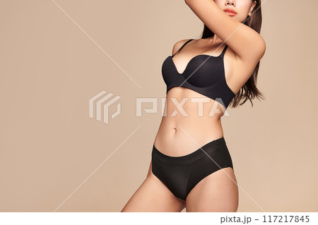Confident beautiful young asian woman posing in black lingerie on beige background, Perfect body, Confident beautiful young asian woman posing in black lingerie on beige background, Perfect body, 117217845