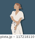 A woman in a flowing white dress stands gracefully by a blue wall 117218110