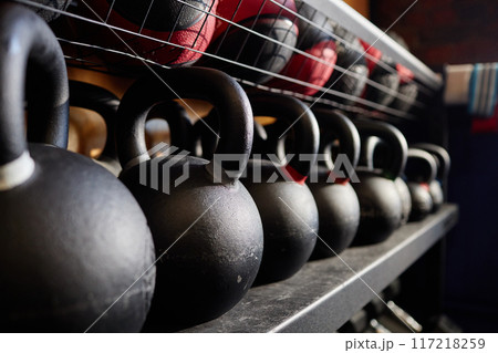 Close up background image of kettlebells in row on equipment rack in weight training gym copy space 117218259