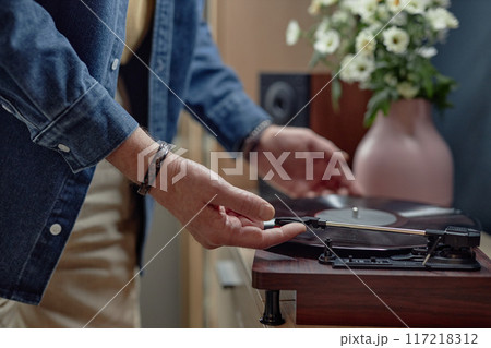 Closeup of unrecognizable senior man setting up record player at home and enjoying music old fashioned way copy space Closeup of unrecognizable senior man setting up record player at home and enjoying music old fashioned way copy space 117218312