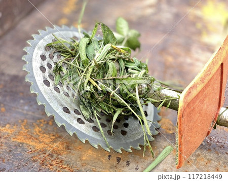 草刈り機の刃と巻き付いた草 117218449