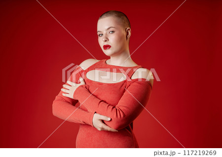 Minimal waist up portrait of sensual vamp girl with short hair posing in studio wearing red dress copy space 117219269
