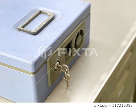 スチールデスクの上に置いた水色の金庫 117219355