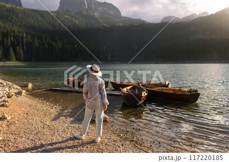 A woman in a hat looks at the boats near the Black Lake in Durmitor 117220185
