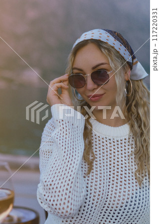 Fashion street style portrait of elegant woman wearing trendy sunglasses, big gold earrings, trendy bandana posing outdoors. Copy, empty space for text Fashion street style portrait of elegant woman wearing trendy sunglasses, big gold earrings, trendy bandana posing outdoors. Copy, empty space for text 117220331