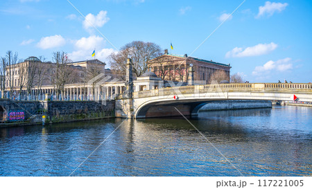 Friedrichs Bridge spans a river in Berlin under a clear blue sky, with nearby historical buildings of Museum Island visible. Berlin, Germany Friedrichs Bridge spans a river in Berlin under a clear blue sky, with nearby historical buildings of Museum Island visible. Berlin, Germany 117221005