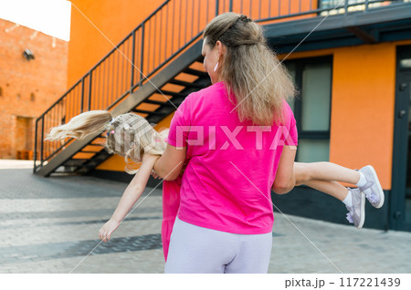 Blonde little girl with cochlear implant playing with her mother outdoor. Hear impairment deaf and health concept. Disability and inclusion. Copy space Blonde little girl with cochlear implant playing with her mother outdoor. Hear impairment deaf and health concept. Disability and inclusion. Copy space 117221439