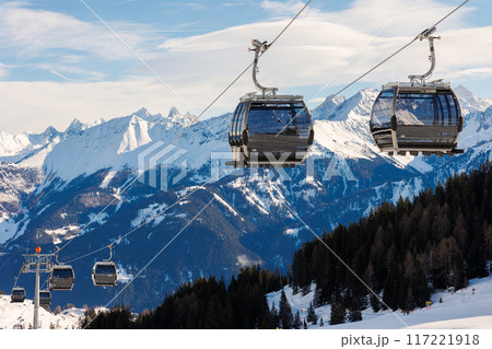 New modern spacious big cabin ski lift gondola against snowcapped forest tree and mountain peaks covered in snow landscape in luxury winter alpine resort. Winter leisure sports, recreation and travel 117221918