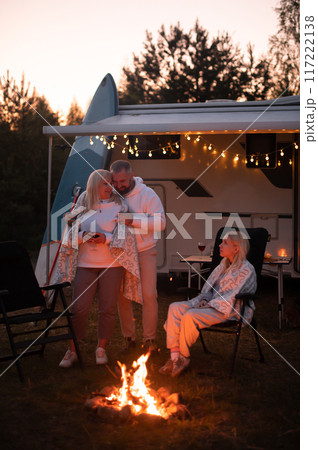 The family is relaxing together by the campfire near their mobile home. Evening family vacation 117222138
