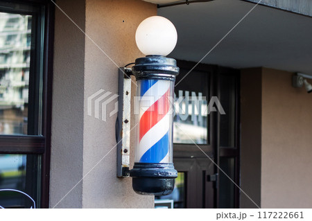 There is a red, white, and blue barber pole attached to the buildings side 117222661