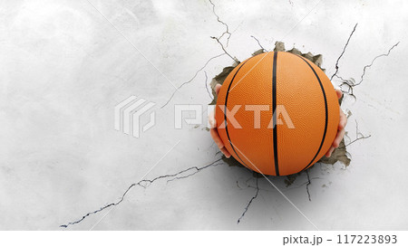 A hand holding a basketball pierced through a cement wall. The strength of the concept of basketball 117223893