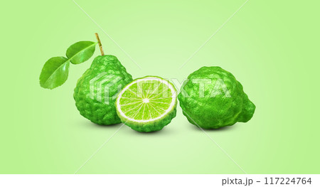 whole bergamot lime leaves and halved with bergamot lime leaves isolated on green background whole bergamot lime leaves and halved with bergamot lime leaves isolated on green background 117224764