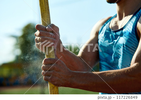 Cropped image of male athlete holding pole with hands in chalk. Determined young man preparing for pole jump, showcasing strength and readiness Cropped image of male athlete holding pole with hands in chalk. Determined young man preparing for pole jump, showcasing strength and readiness 117226849