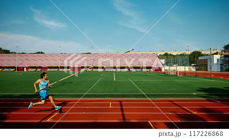 Motivated young athlete practicing for pole vaulting championship, competitive and focused man in motion, running with pole at stadium 117226868