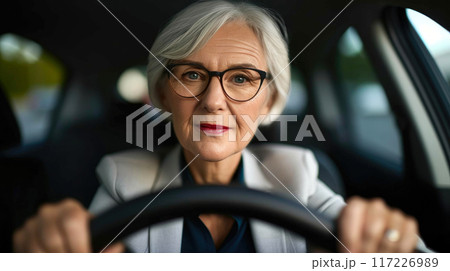 Graceful Leadership: Senior Woman Behind the Car Wheel 117226989