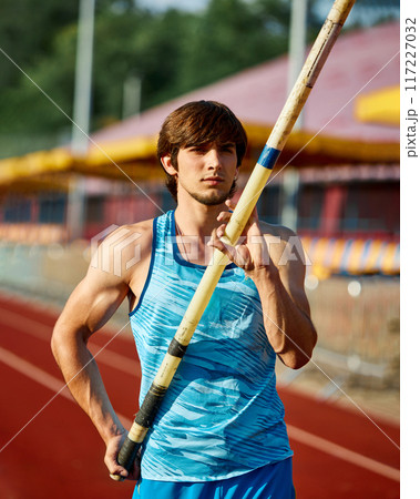 Focused man, pole jump athlete working on pole vaulting technique, growing skills for competition, training at outdoor stadium Focused man, pole jump athlete working on pole vaulting technique, growing skills for competition, training at outdoor stadium 117227032