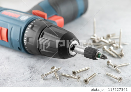 Professional cordless drill screwdriver and screws close-up Professional cordless drill screwdriver and screws close-up 117227541