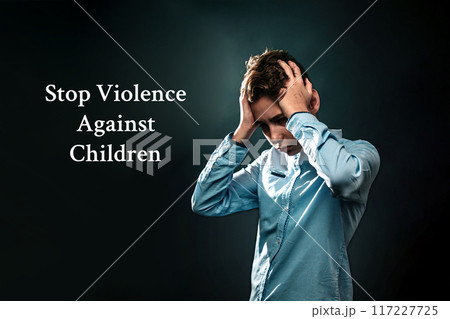 The concept of domestic violence. A teenage boy holds his hands over his head, experiencing stress. Text Stop violence against children . Black background The concept of domestic violence. A teenage boy holds his hands over his head, experiencing stress. Text Stop violence against children . Black background 117227725
