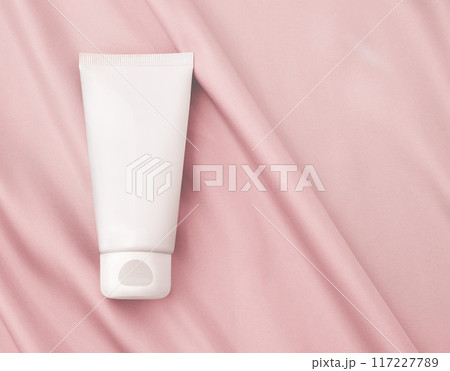 White Cosmetic Tube Positioned Gracefully on a Pink Fabric Background 117227789