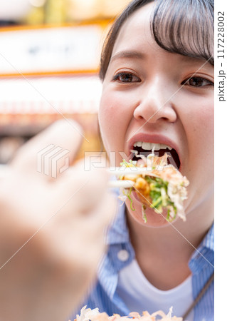明るい屋外でたこ焼きを食べる女性|大阪府大阪市道頓堀にて 明るい屋外でたこ焼きを食べる女性|大阪府大阪市道頓堀にて 117228002
